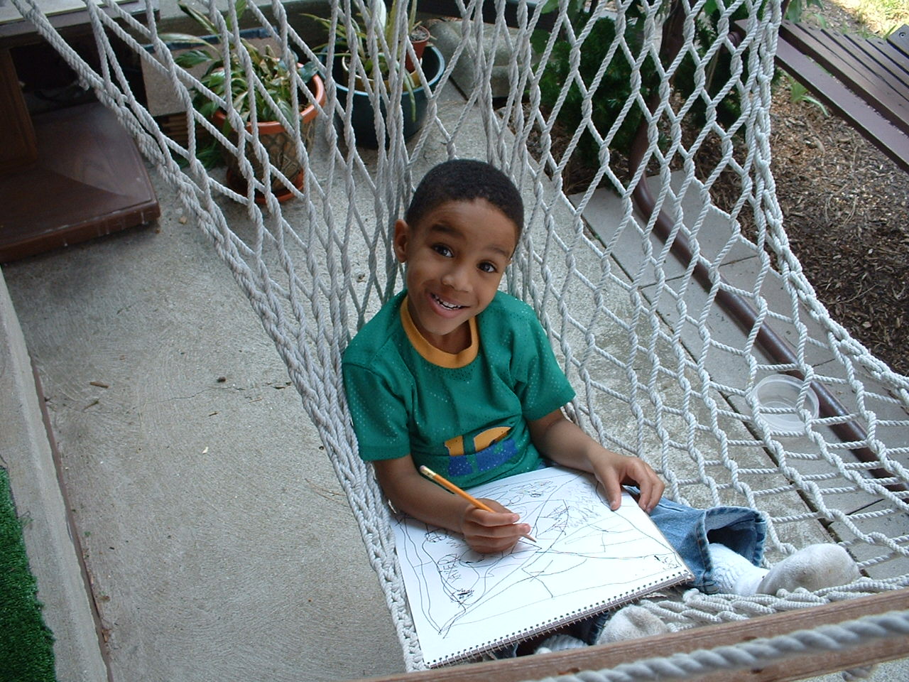 Young Xavier sketching in a backyard hammock